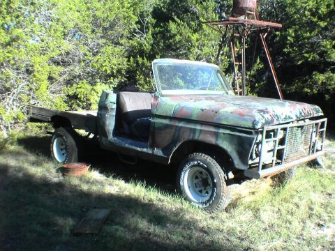 1991 Ford Bronco - This weathered pickup truck, painted in camouflage, sits in a grassy outdoor area. It appears to be missing its doors and front grille.