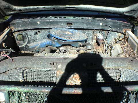 1991 Ford Bronco - The engine bay of an older vehicle shows a blue air cleaner assembly and a heavily rusted grille.