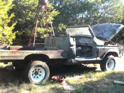 1991 Ford Bronco - This heavily modified flatbed truck has camouflage paint and its hood is open.