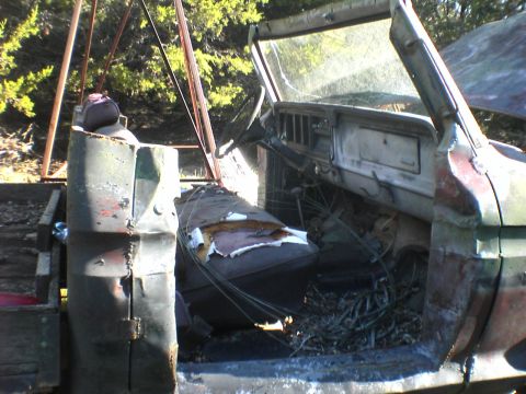 1991 Ford Bronco - The interior of a heavily damaged truck shows torn upholstery and a cluttered dashboard.