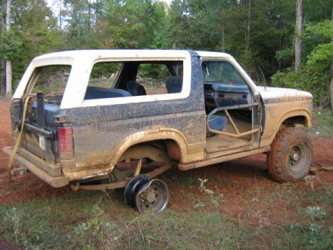 1986 Ford Bronco - This heavily modified 1986 Ford Bronco appears to be in rough condition, with a missing door and a detached wheel.