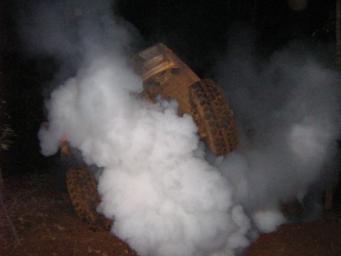 1986 Ford Bronco - Off-road vehicle stuck in mud, emitting white smoke.