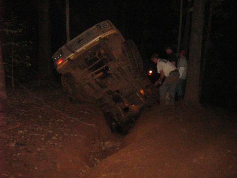 1986 Ford Bronco - A vehicle is stuck in a ditch at night, with several people observing the situation.