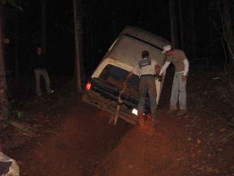 1986 Ford Bronco - A group of people attempt to recover a vehicle that has become stuck in the mud on a dark, wooded trail.