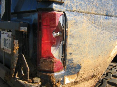 1986 Ford Bronco - Close-up of a damaged taillight on a heavily soiled SUV, with a Texas license plate visible.