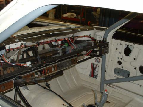 2005 Ford Mustang - The dashboard and door panel are removed, revealing the car's internal wiring and a roll cage structure.