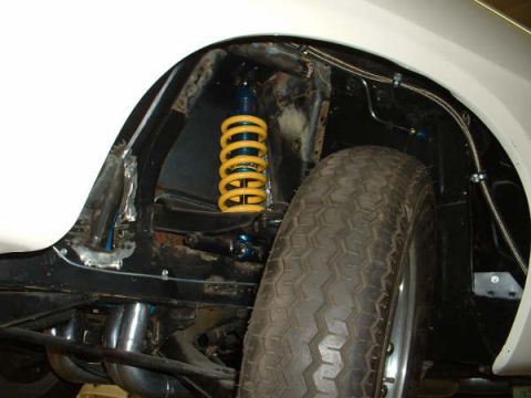 2005 Ford Mustang - This photo shows the rear suspension and wheel well of a vehicle, including a yellow shock absorber and exhaust system.