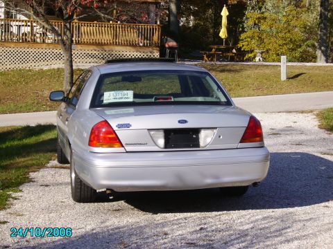 2002 Ford Crown Victoria - A silver Ford Crown Victoria is shown from the rear on a gravel surface with a house and trees in the background.