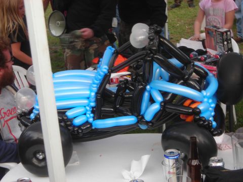 1997 Jeep TJ - A balloon sculpture resembling a vehicle is displayed on a table, with onlookers in the background.