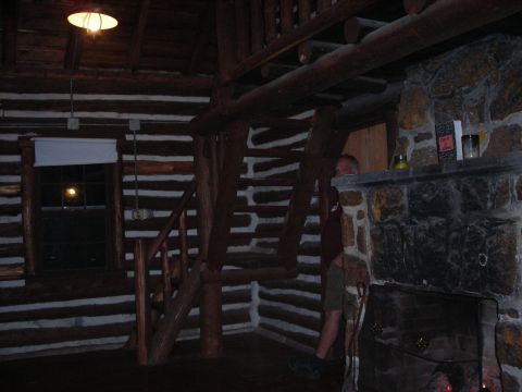 1997 Jeep TJ - Log cabin interior features a stone fireplace and wooden staircase, with a person visible on the upper level.
