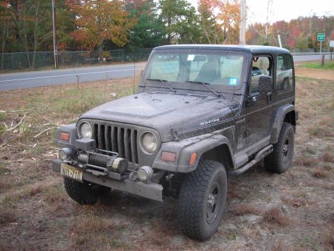 1997 Jeep TJ - This Jeep Wrangler is parked off the side of a road, showing its front and side profile with a winch mounted on the bumper.
