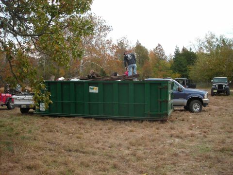 1997 Jeep TJ - A 1997 Jeep TJ is seen parked in a grassy area next to a large green dumpster.