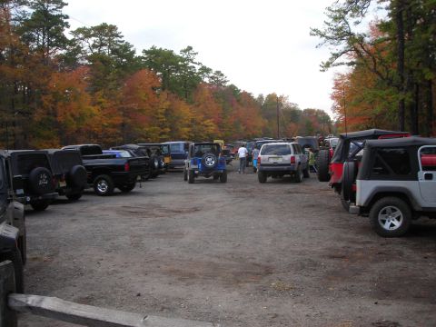 1997 Jeep TJ - A variety of Jeeps and SUVs are parked in a lot surrounded by trees displaying autumn colors.