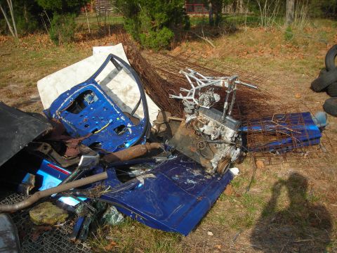 1997 Jeep TJ - Scrap heap with car doors, an engine, and various metal parts scattered on the ground.