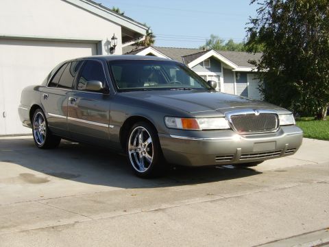 2000 Mercury Grand Marquis - A gray 2000 Mercury Grand Marquis is parked in front of a garage.