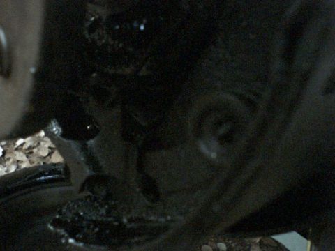 1972 Ford Ranchero - A dark, blurry view of a vehicle's undercarriage, with gravel on the ground.
