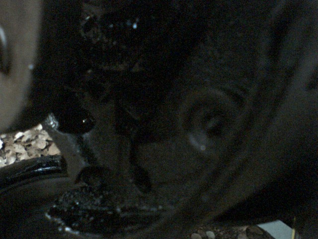 Undercarriage of a dark vehicle with gravel visible