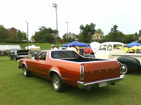 1979 Ford Ranchero - This orange Ford Ranchero is parked on a grassy field with other vehicles and tents visible.
