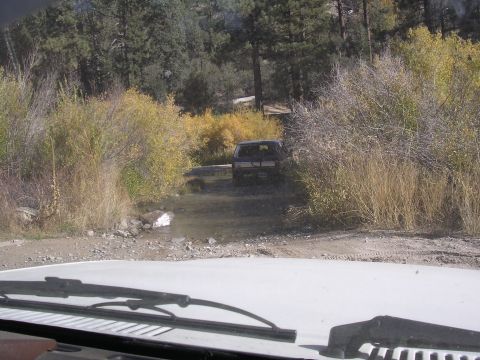 1985 Toyota 4Runner - SUV navigates a water crossing surrounded by trees and brush during the fall.