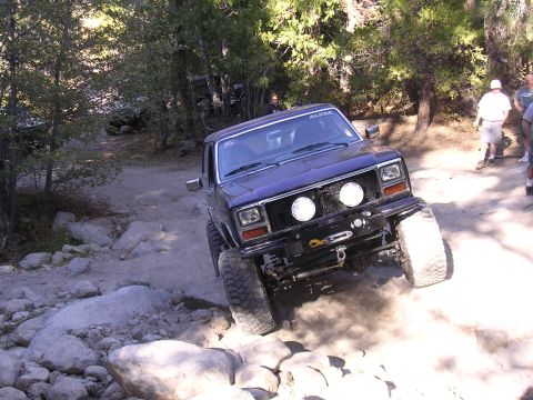 1985 Toyota 4Runner - This truck is navigating a rocky trail, kicking up dust as it goes.