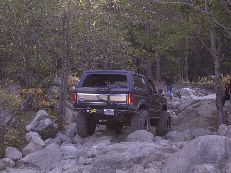Dark blue SUV with lifted suspension and off-road tires navigating rocky terrain