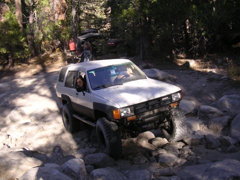 1985 Toyota 4Runner - A 1985 Toyota 4Runner navigates a rocky trail with trees in the background.