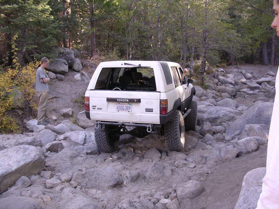 White 1985 Toyota 4Runner with off-road tires navigating a rocky path