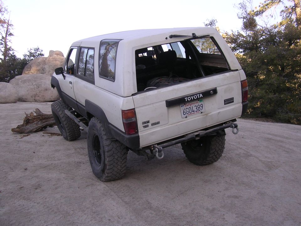 White Toyota 4Runner with a cap, lifted with large tires, on a dirt road