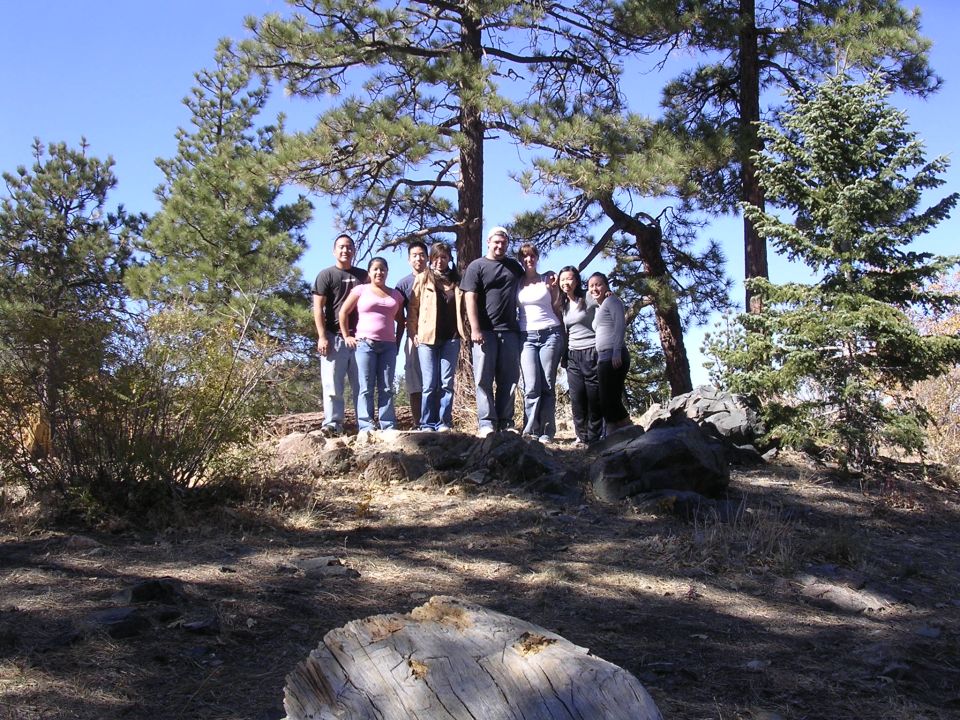 Group of people posing for a photo outdoors with trees and a clear blue sky