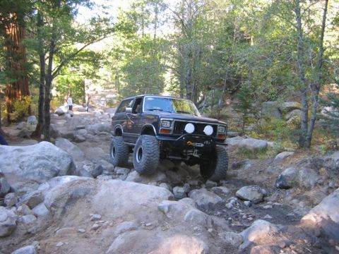 1985 Ford Bronco - This lifted 1980s Ford Bronco tackles a challenging rocky off-road path.