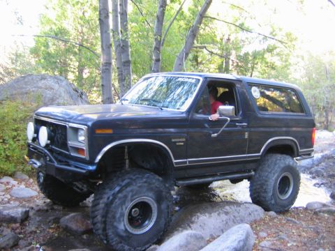 1985 Ford Bronco - This lifted Ford Bronco navigates a rocky stream bed, its off-road capabilities.