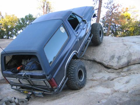 1985 Ford Bronco - This modified SUV is shown navigating a challenging rocky terrain, with its large tires providing traction.