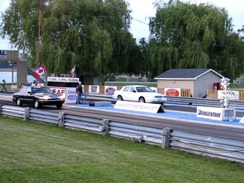 2003 Ford Crown Victoria - Two Ford Crown Victorias are lined up on a drag strip, ready for a race.