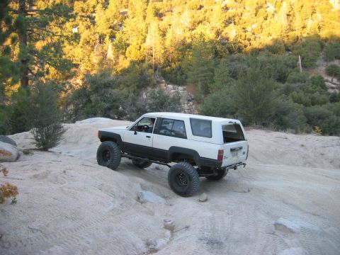 1985 Ford Bronco - Modified Toyota 4Runner navigates a challenging off-road trail with steep inclines and loose terrain.