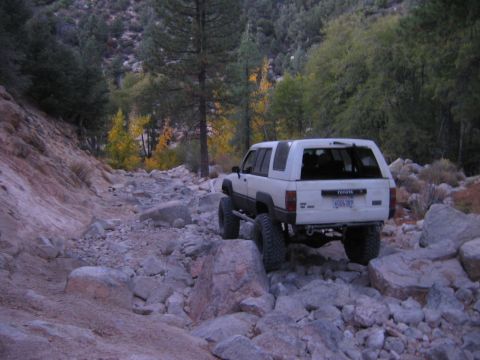 1985 Ford Bronco - White Toyota 4Runner tackling a challenging rocky trail in a mountainous area.