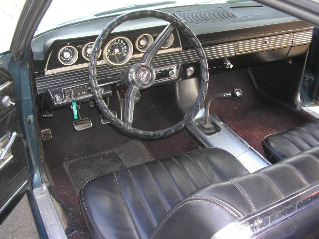 Car interior with black seats, dashboard, and steering wheel. Readable text on radio