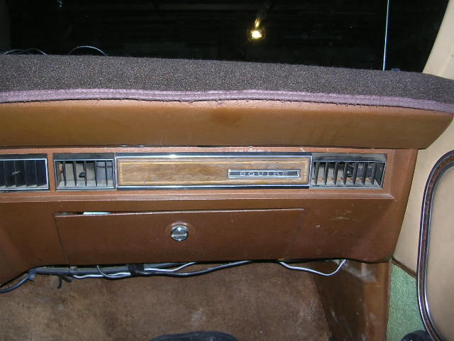 Dashboard with air vents, wood trim, and a glove compartment