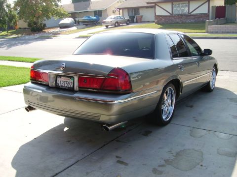2000 Mercury Grand Marquis - Gray Mercury Grand Marquis full-size sedan, rear three-quarter view with dual exhaust and aftermarket chrome wheels.