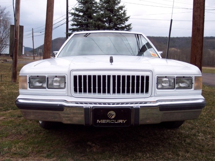 White Mercury sedan front view with vertical-bar grille and Mercury badge on the bumper