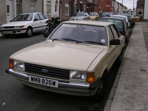 Beige Ford sedan with UK plate WMB 826W parked on a British terraced street