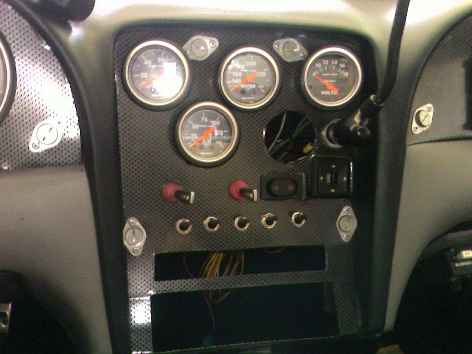 Custom center dash panel with four Auto Meter gauges and toggle switches in gray interior