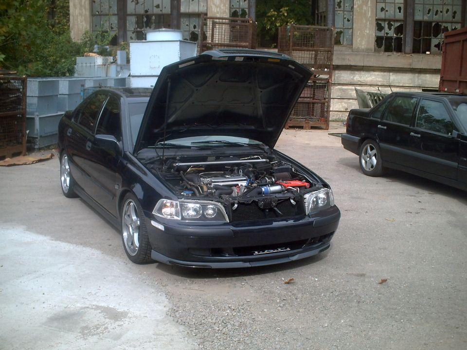 Dark sedan with hood open, showing engine bay. Another black sedan parked behind it