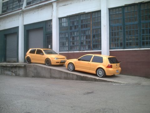 2006 Volkswagen GTI - Two yellow Volkswagen Golf Mk4 hatchbacks are parked on a ramp outside an industrial building.
