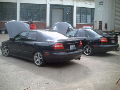 2006 Volkswagen GTI - Two black sedans are parked with their hoods open in front of an industrial building.