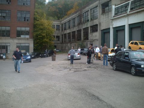 2006 Volkswagen GTI - Cars gathered outside an abandoned industrial building, with people milling about.