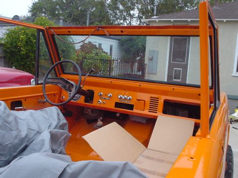 1977 Ford Bronco - The interior of an orange 1977 Ford Bronco is shown with the doors and top removed.