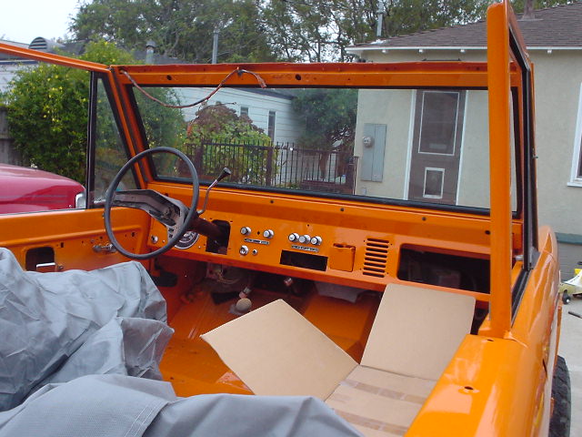 Orange 1977 Ford Bronco interior with dashboard, steering wheel, and seats covered