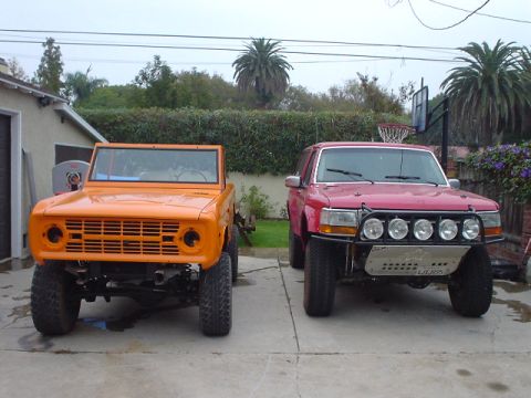 1977 Ford Bronco - Two Ford Broncos, one older and one newer, are parked side-by-side in a driveway.