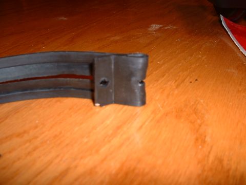 1978 Ford Mustang II - A close-up view of a rubber seal and its mounting bracket, resting on a wooden surface.