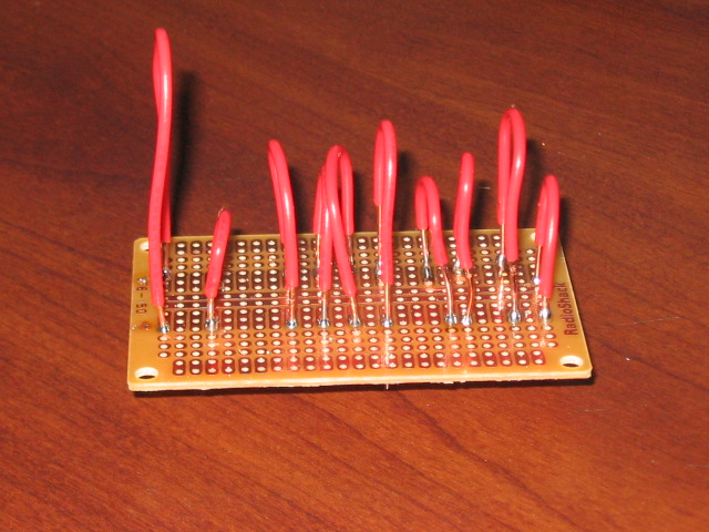 Circuit board with multiple red wires sticking up from it